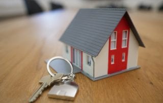 A house model with keys on a table. Learn how to make an offer and make this home yours. A comprehensive guide to the home-buying process.