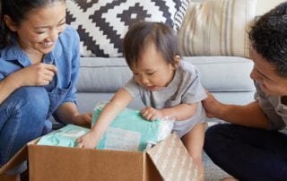 Moving up: Young family with baby opening a box